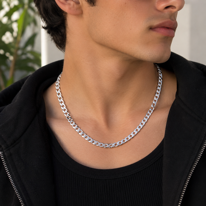 A close-up of a man wearing a silver Cuban link chain necklace over a black shirt and black zip-up hoodie.