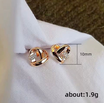 A pair of rose gold heart-shaped stud earrings with small clear crystal accents, displayed on a white fabric background with a dimension line indicating 10mm size and text reading about: 1.9g.