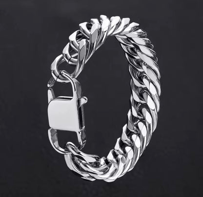 A chunky silver Cuban link chain bracelet with a polished clasp, shown on a dark black background.