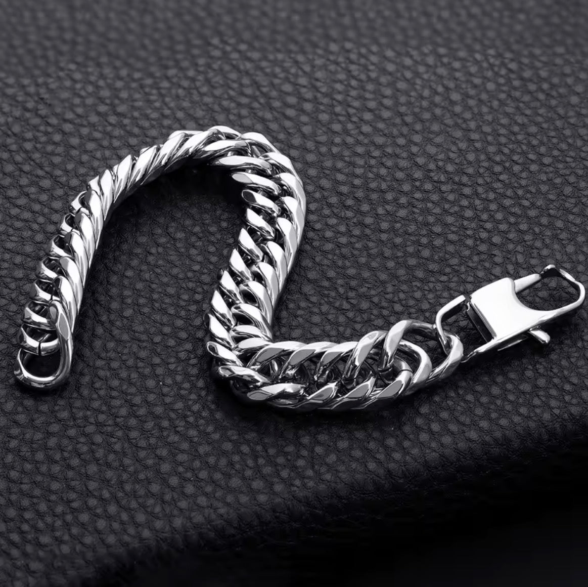 Silver chain bracelet on a textured black surface.