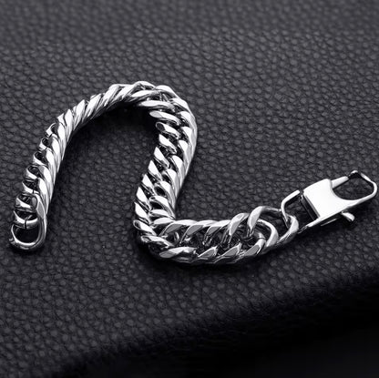 Silver chain bracelet on a textured black surface.