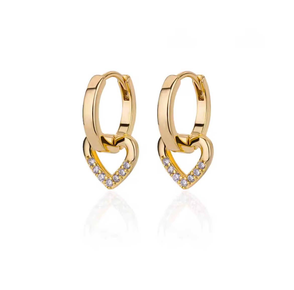 
A pair of gold huggie hoop earrings with interlocking heart designs, featuring a pavé diamond heart at the bottom of each earring, set against a clean white background with a soft reflection.